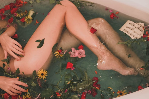woman soak in a bathtub with bay leaves floating